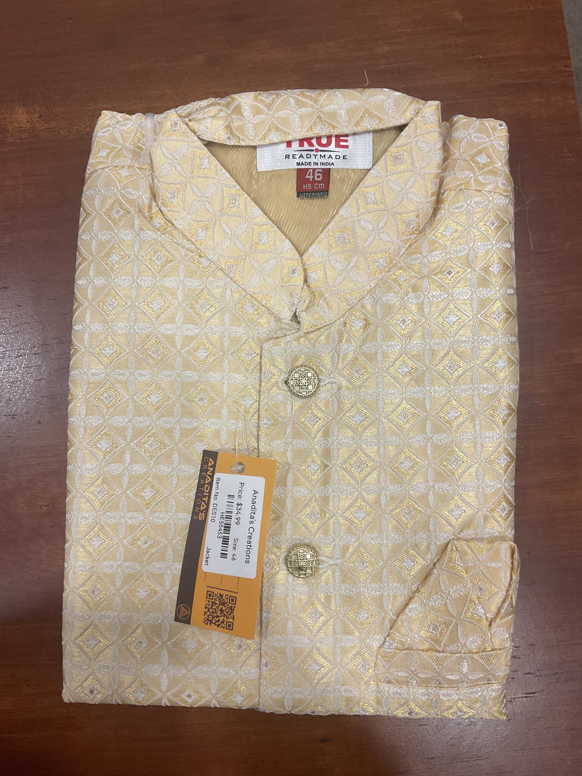 Folded cream and gold Nehru jacket with a geometric floral pattern, decorative buttons and a Size 46 label.