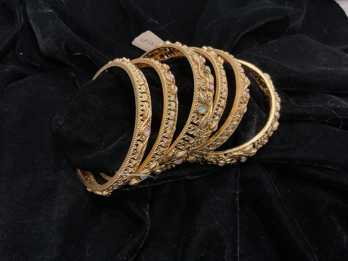 Golden-colored narrow bangles with patterned detailing and pale pink and mint accents.