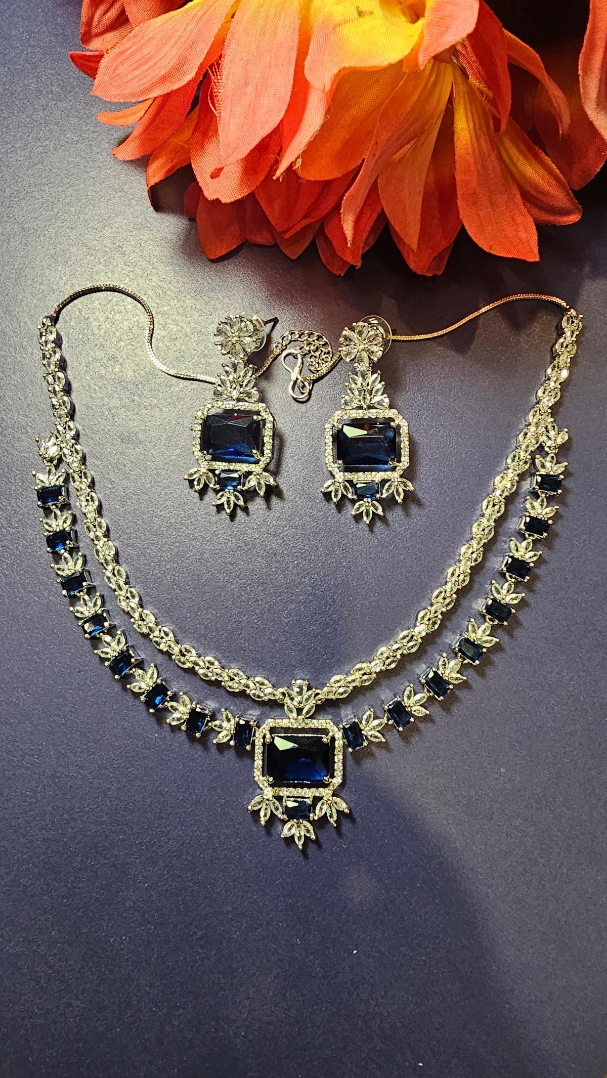 layered necklace design with blue rectangular stones and two earrings.