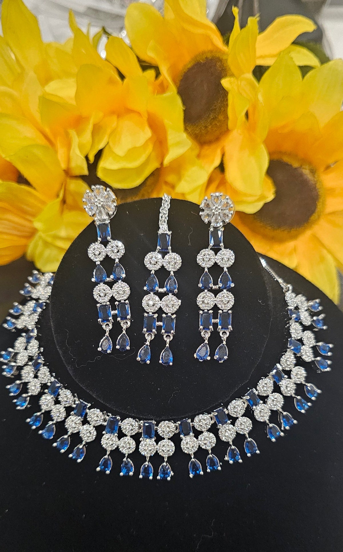 silver-tone necklace with circular links and colored stone drops in blue with two earrings and center forehead ornament shown.