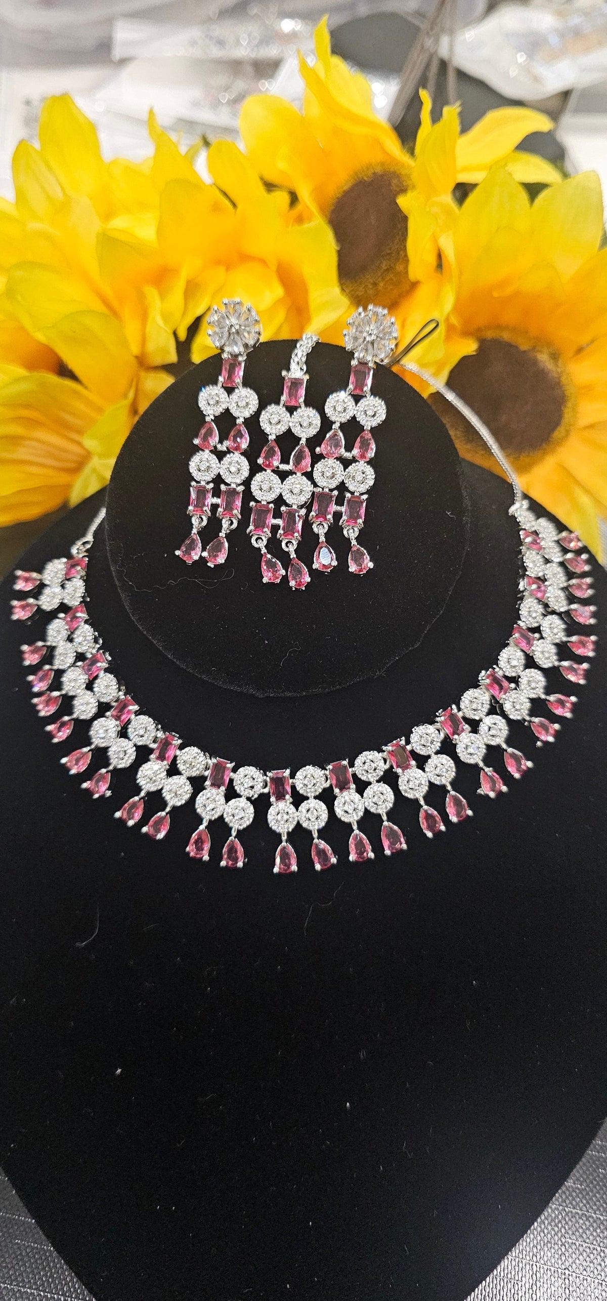 Silver-tone necklace with pink/red-toned rectangular and teardrop stones, circular links; two earrings and center forehead ornament shown.