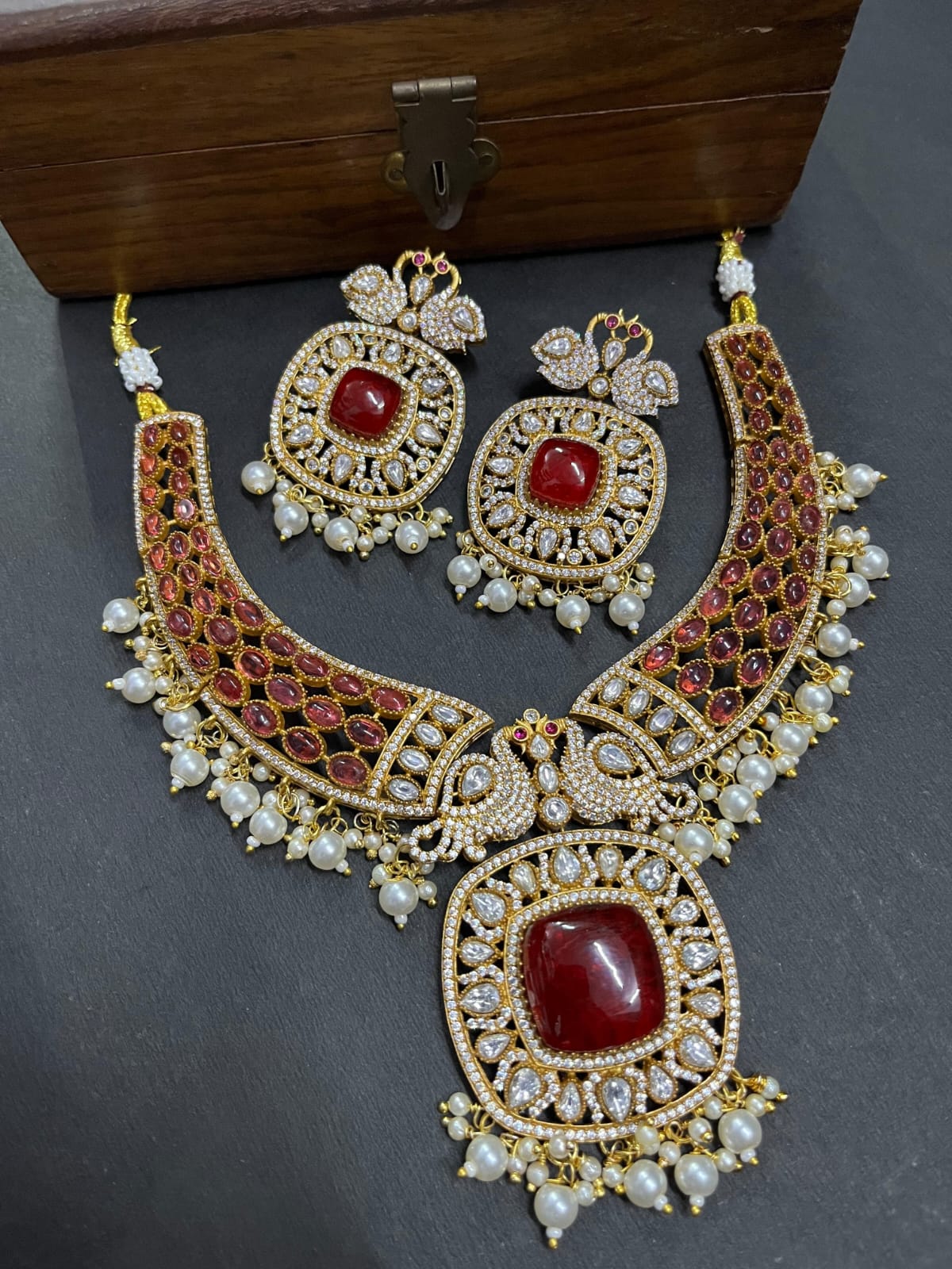 Gold-tone necklace and two earrings; red rounded rectangular center stones, red side accents, white bead fringe and bird motifs.