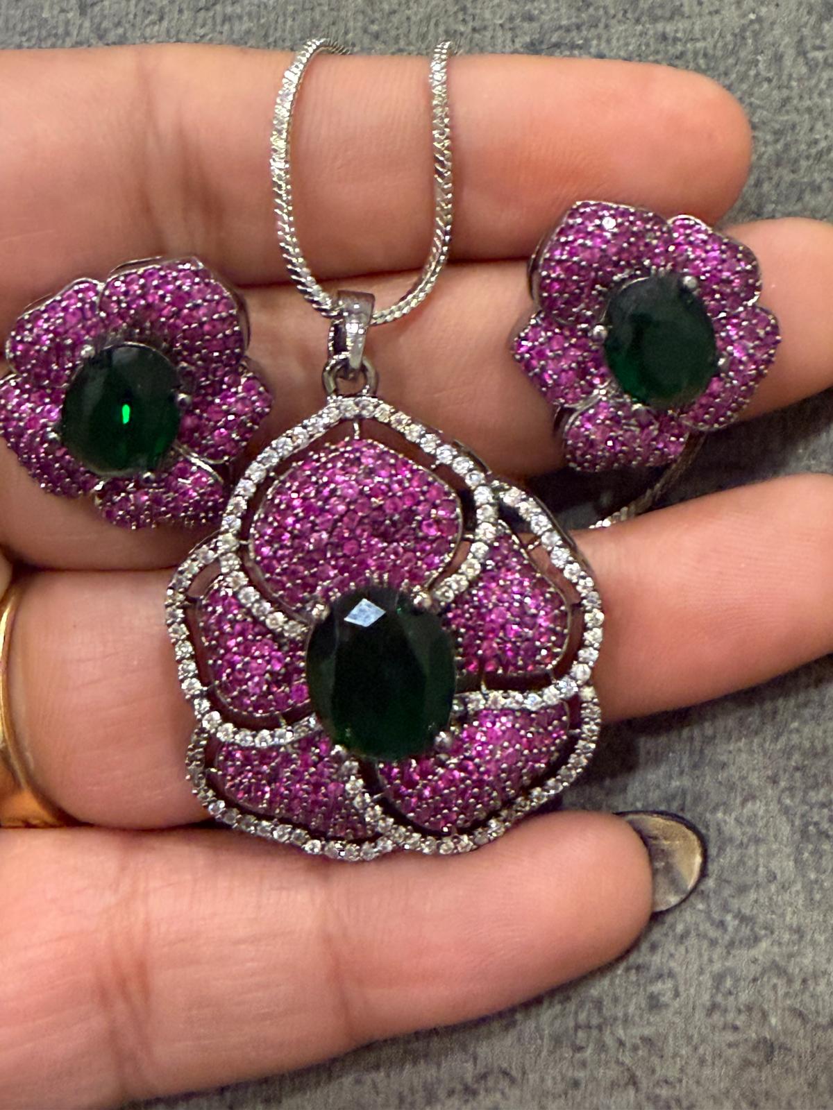 flower pendant and studs with purple/pink small stones and dark green centers.