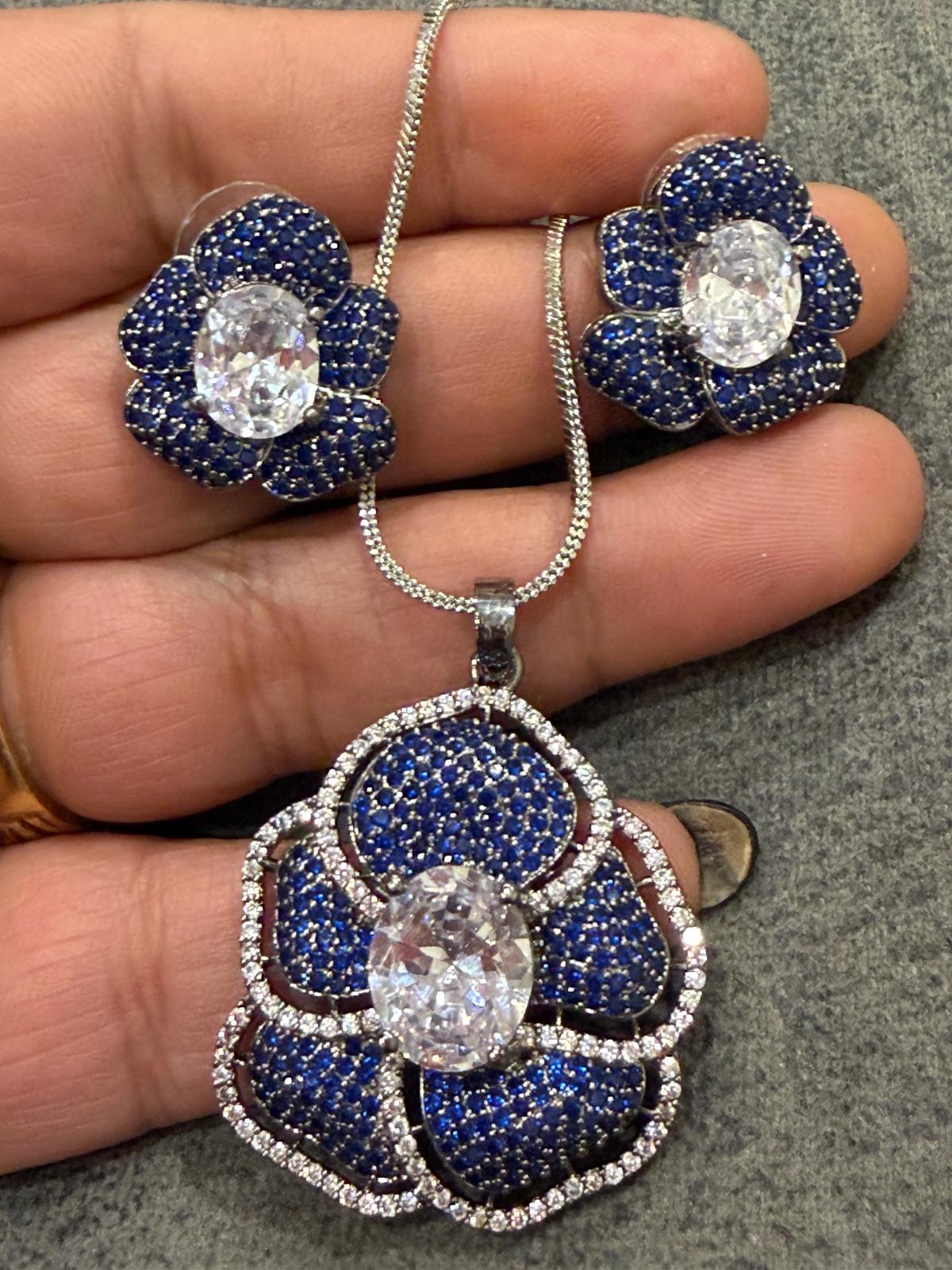 flower pendant and studs with blue small stones and clear centers.