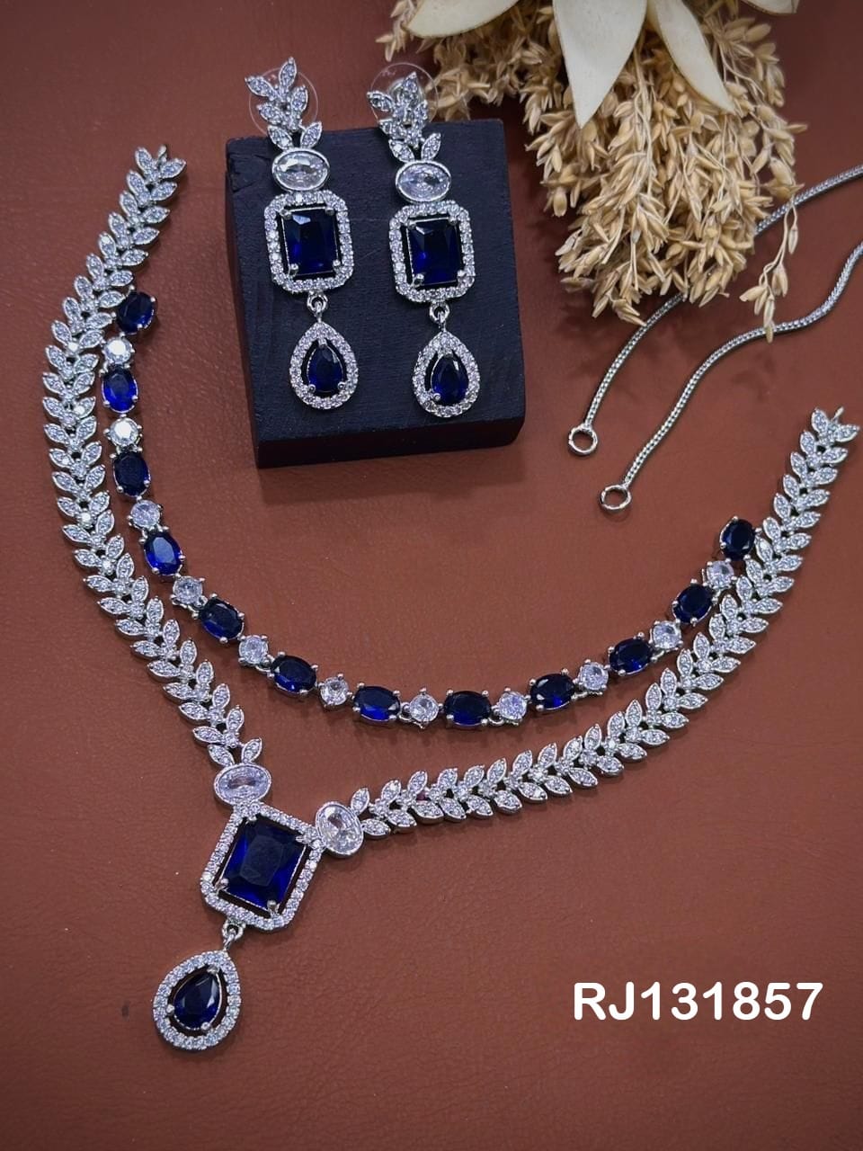 layered leaf design with blue stones and two earrings.