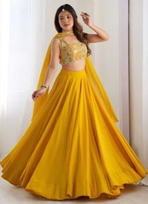Yellow flared skirt, cropped sleeveless embellished top and yellow drape on a model.