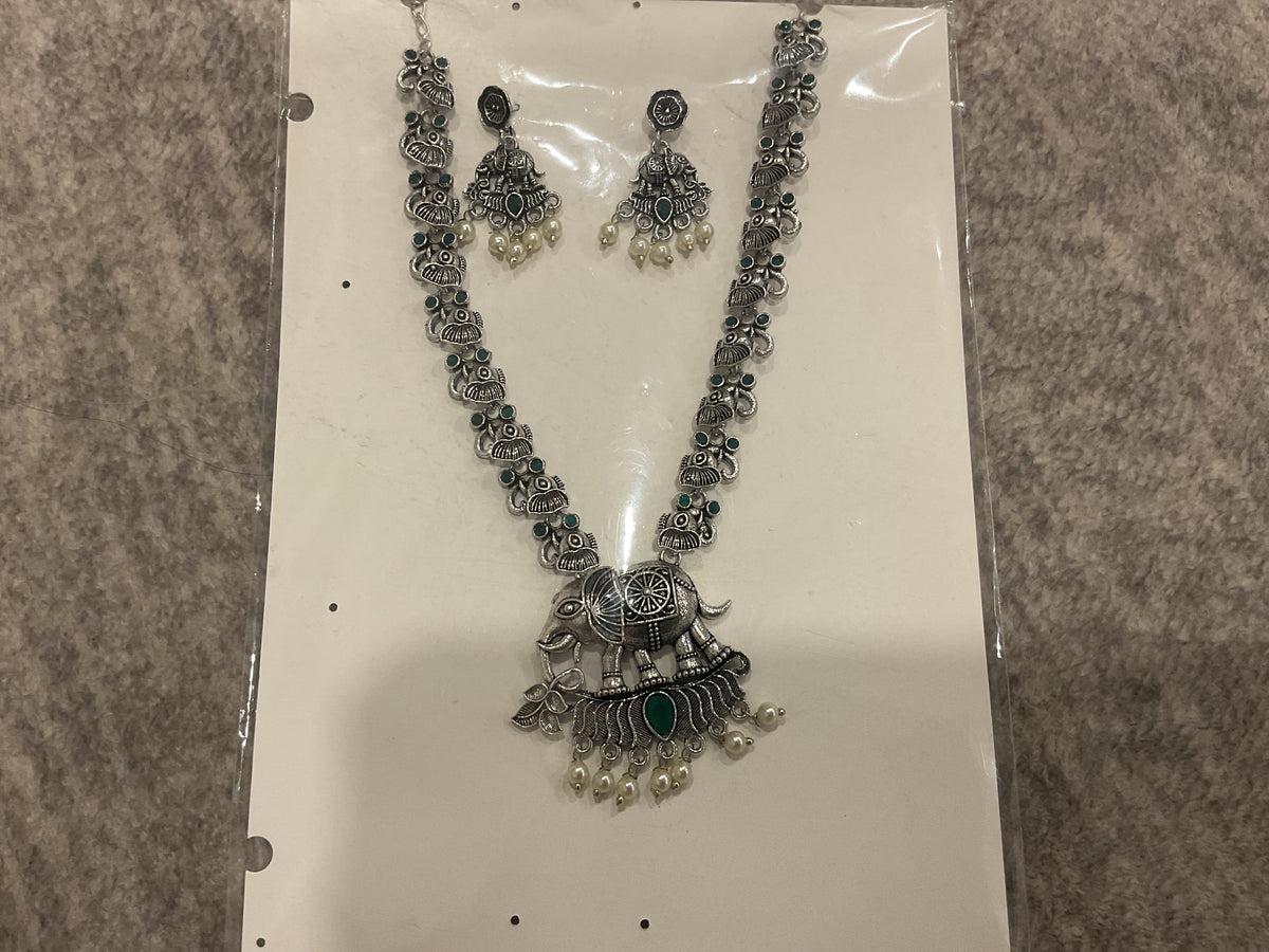 Green long necklace with silver-tone animal links, an elephant pendant, off-white bead drops and matching earrings.