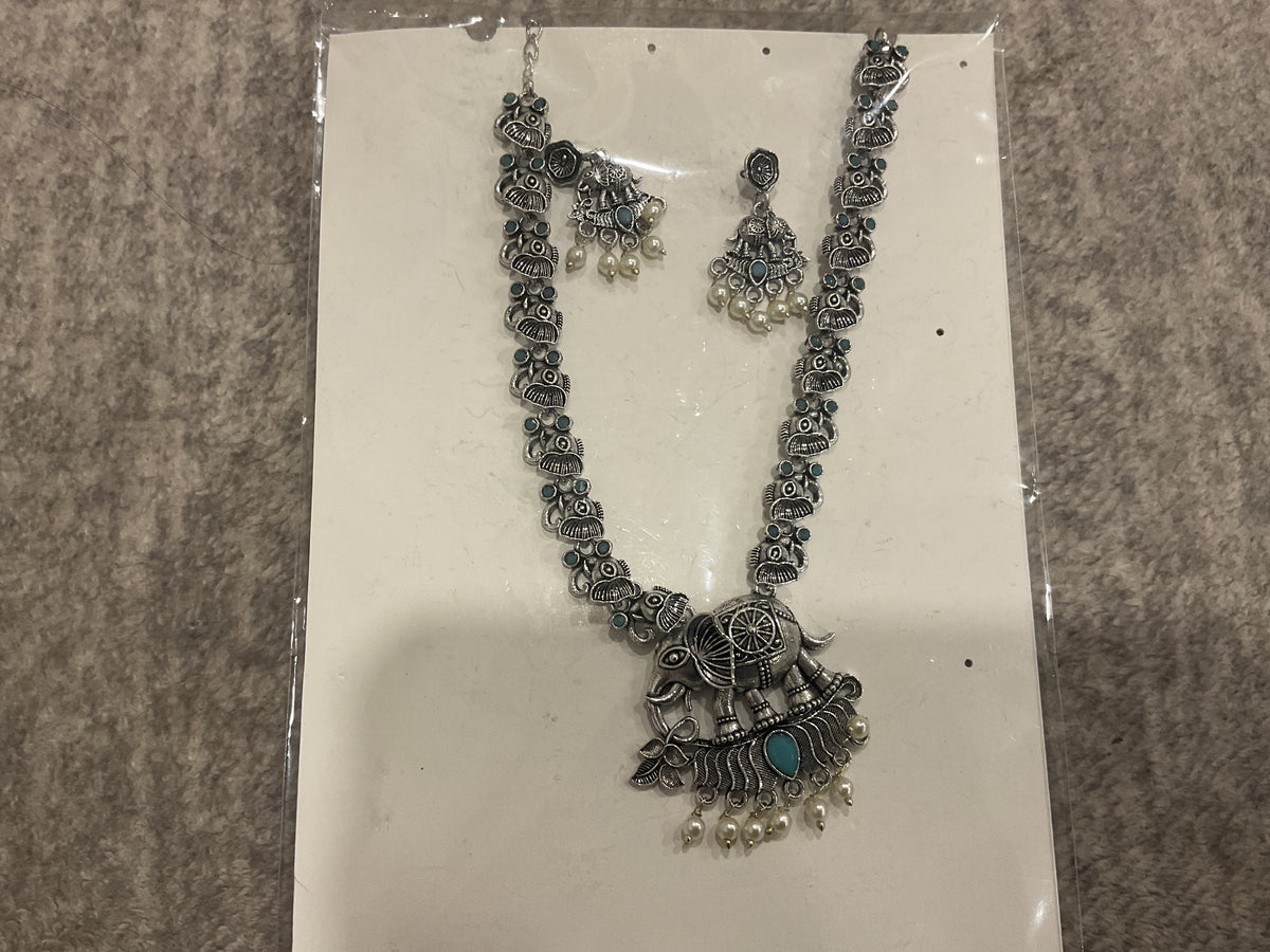 Turquoise-blue long necklace with silver-tone animal links, an elephant pendant, off-white bead drops and matching earrings.