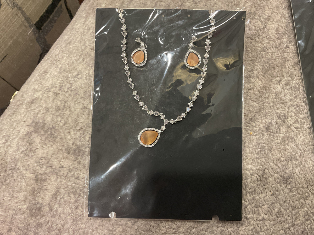 Peach teardrop pendant necklace with silver-tone links, clear accents and matching photographed teardrop earrings.