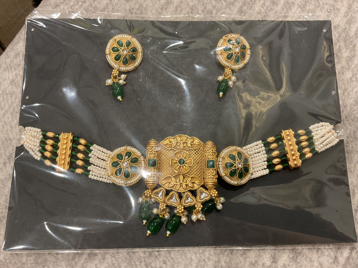 Gold-tone choker with green floral round inserts, an ornate centerpiece, off-white bead strands, green drops and matching photographed earrings.