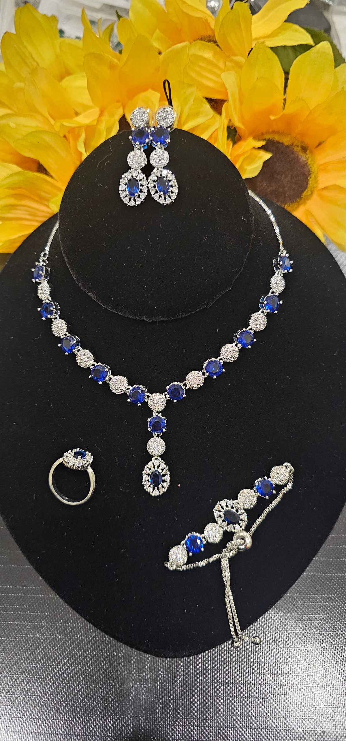 Royal Blue necklace with alternating colored centers and clear clusters with a central drop, shown with coordinating jewelry.