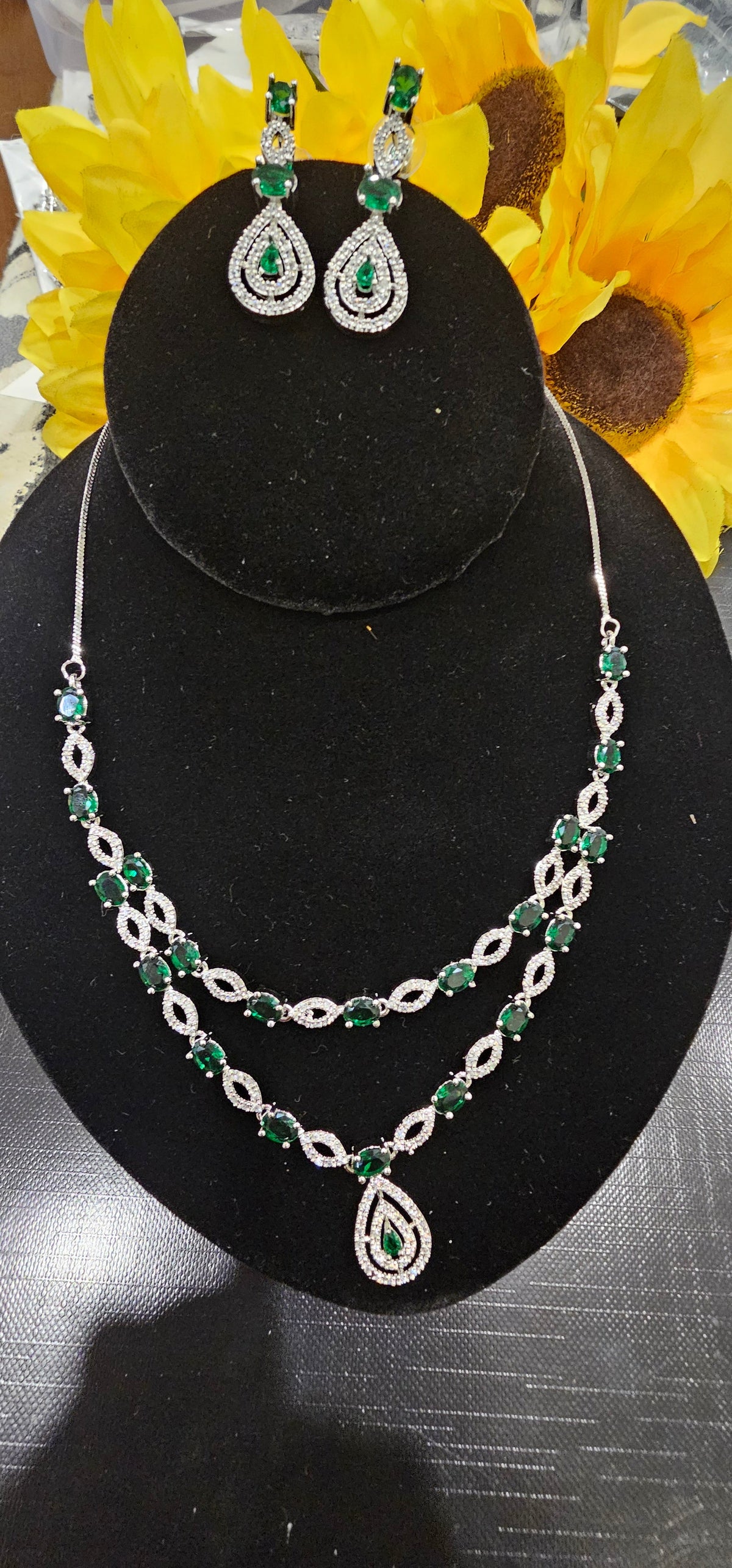 Green necklace with two layers of oval colored accents and open marquise-shaped links with a teardrop pendant, shown with coordinating jewelry.