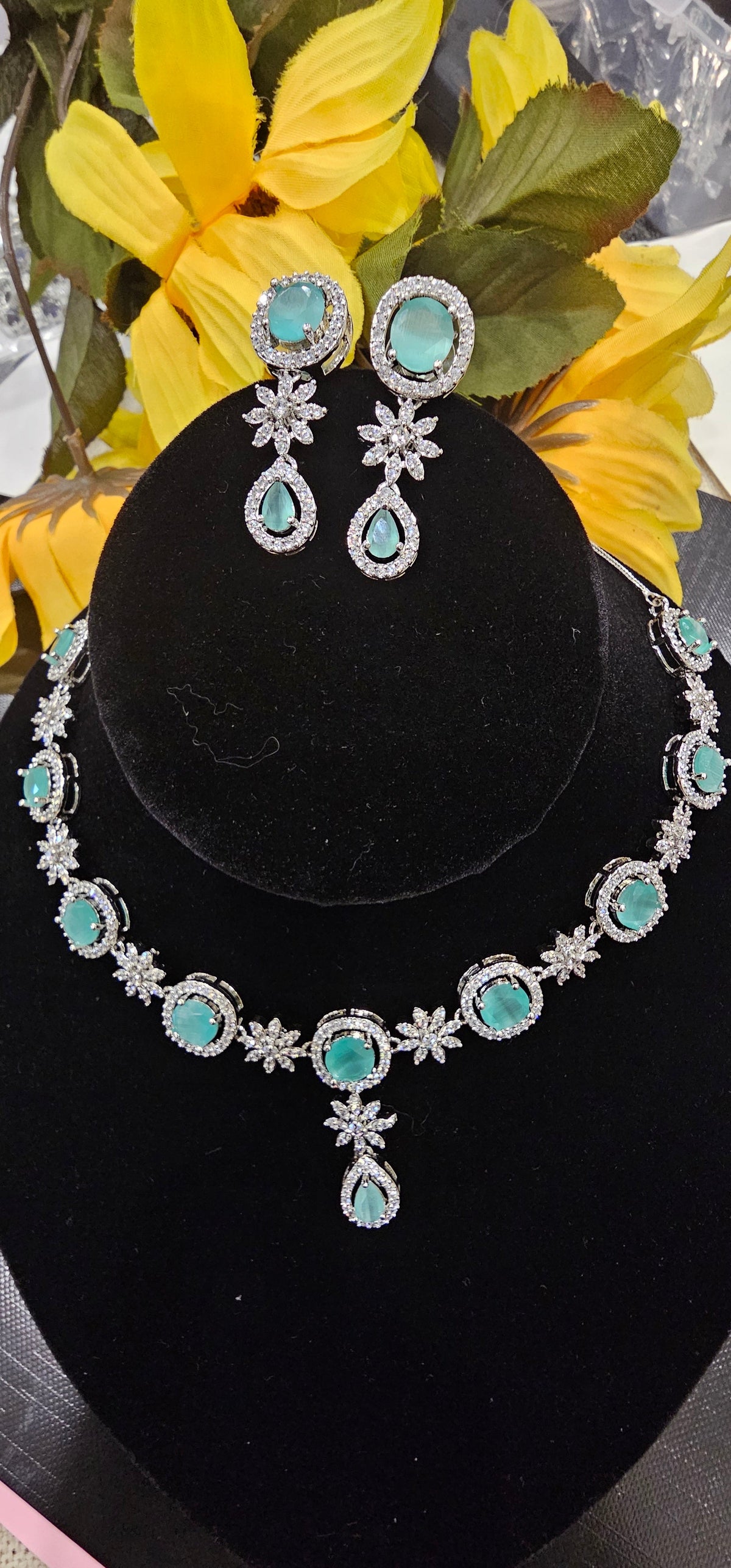 Mint Green necklace with oval colored accents alternating with clear flower-shaped links and a teardrop drop, shown with coordinating jewelry.