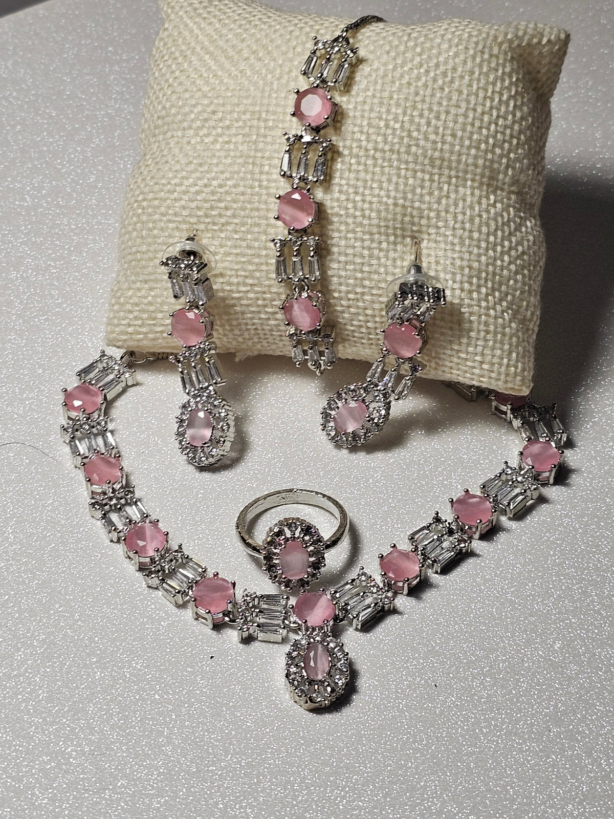 Pink necklace with oval colored centers, clear rectangular accents and a central oval drop, shown with coordinating jewelry.