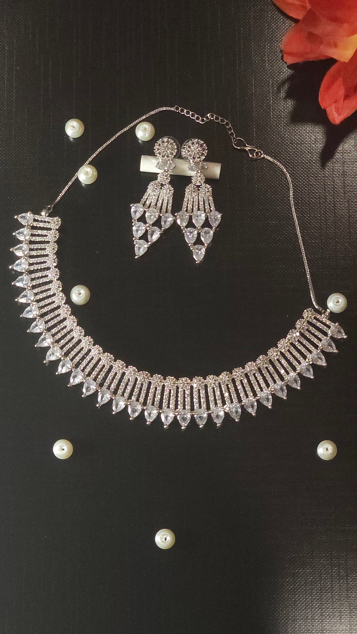 Clear necklace with a curved collar of clear accents with a row of colored teardrop-shaped drops, shown with coordinating jewelry.