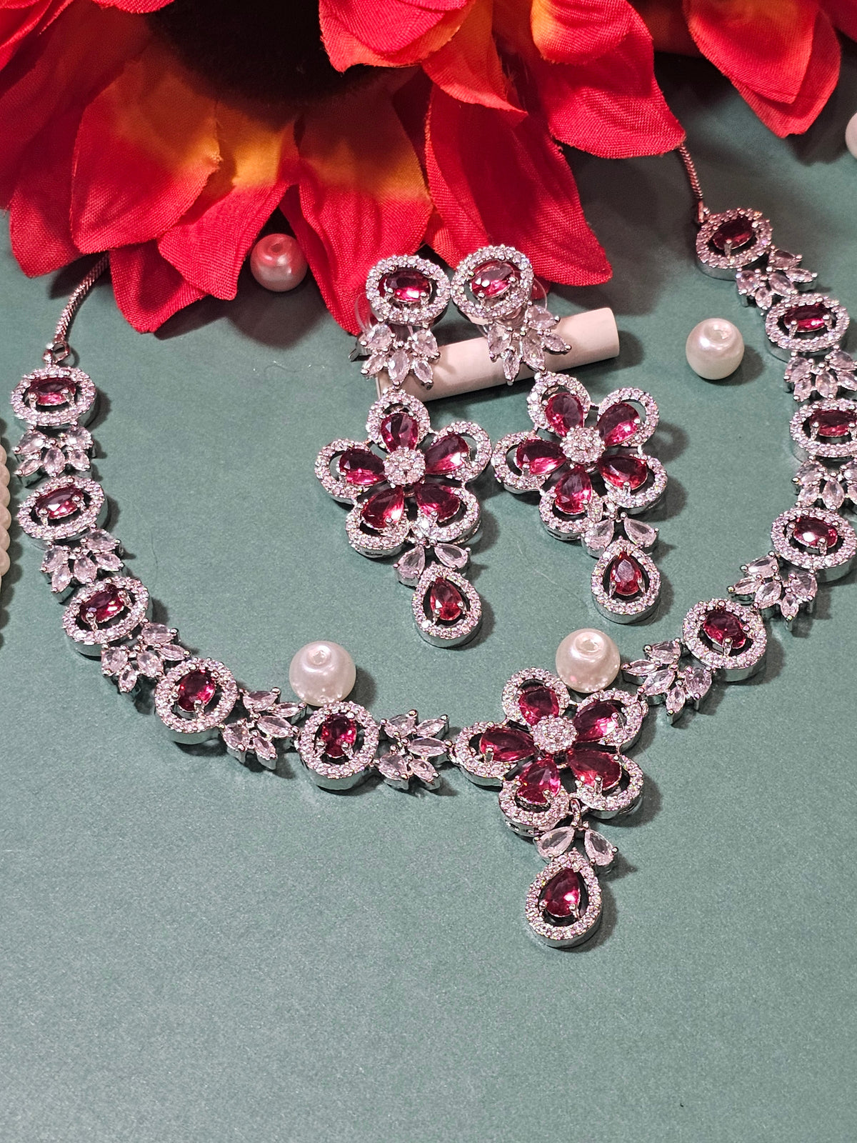 Rani Pink necklace with a flower-shaped pendant, oval colored accents and a teardrop drop, shown with coordinating jewelry.