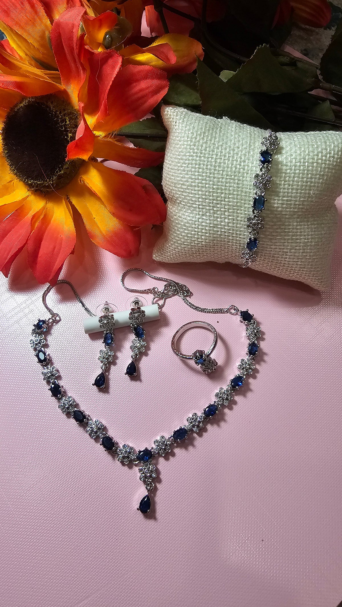 navy blue necklace with alternating colored accents and small clear flower-shaped links with a central drop, shown with coordinating jewelry.