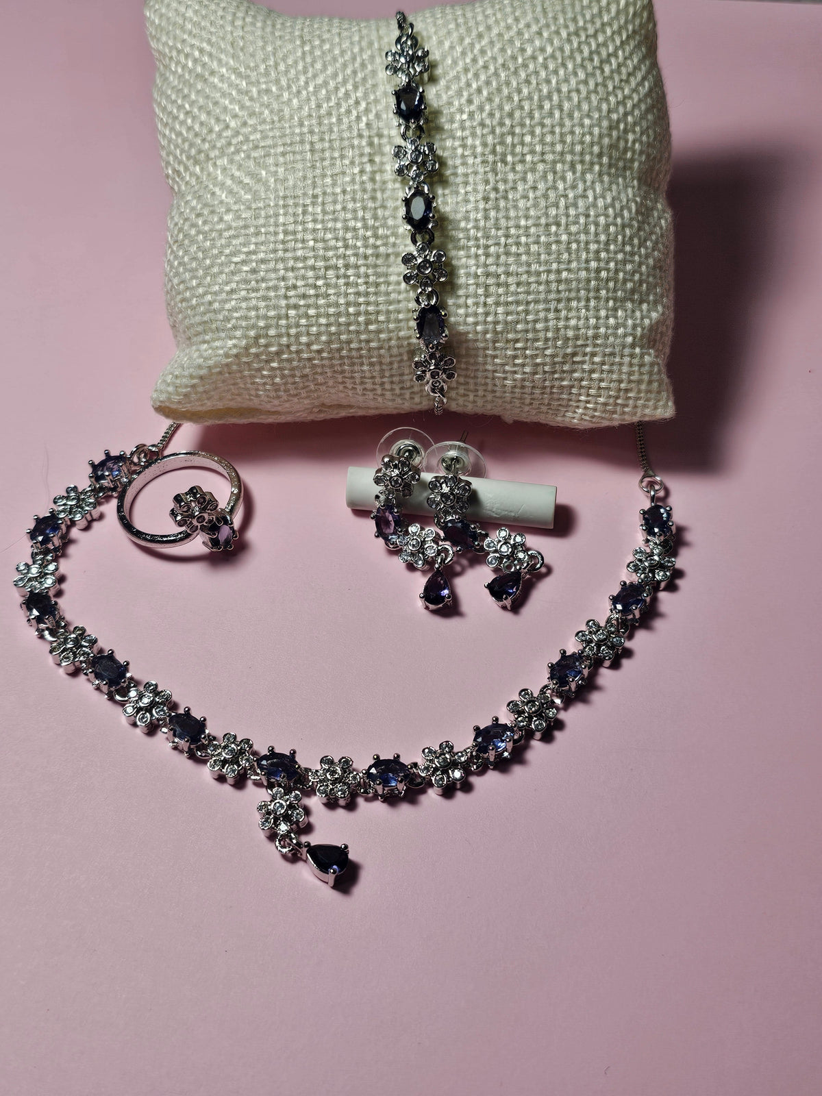 purple necklace with alternating colored accents and small clear flower-shaped links with a central drop, shown with coordinating jewelry.
