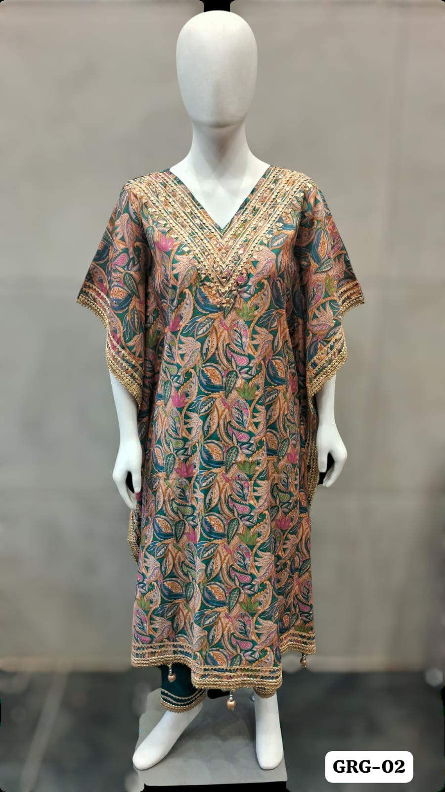Teal Green kaftan with multicolor leaf motifs, wide sleeves and a trimmed V-neckline, shown on a mannequin.