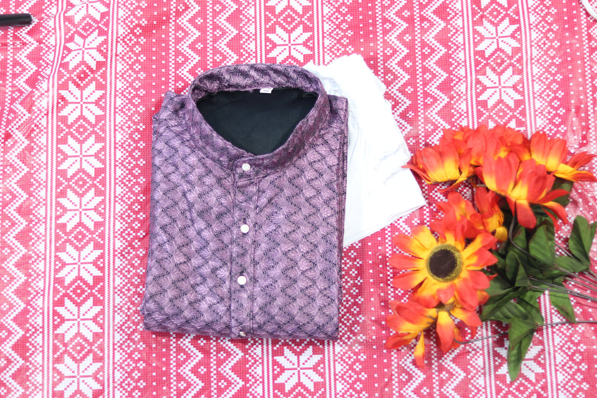 Folded lavender kurta with textured diamond pattern, a band collar and front buttons, arranged beside white fabric and decorative flowers.