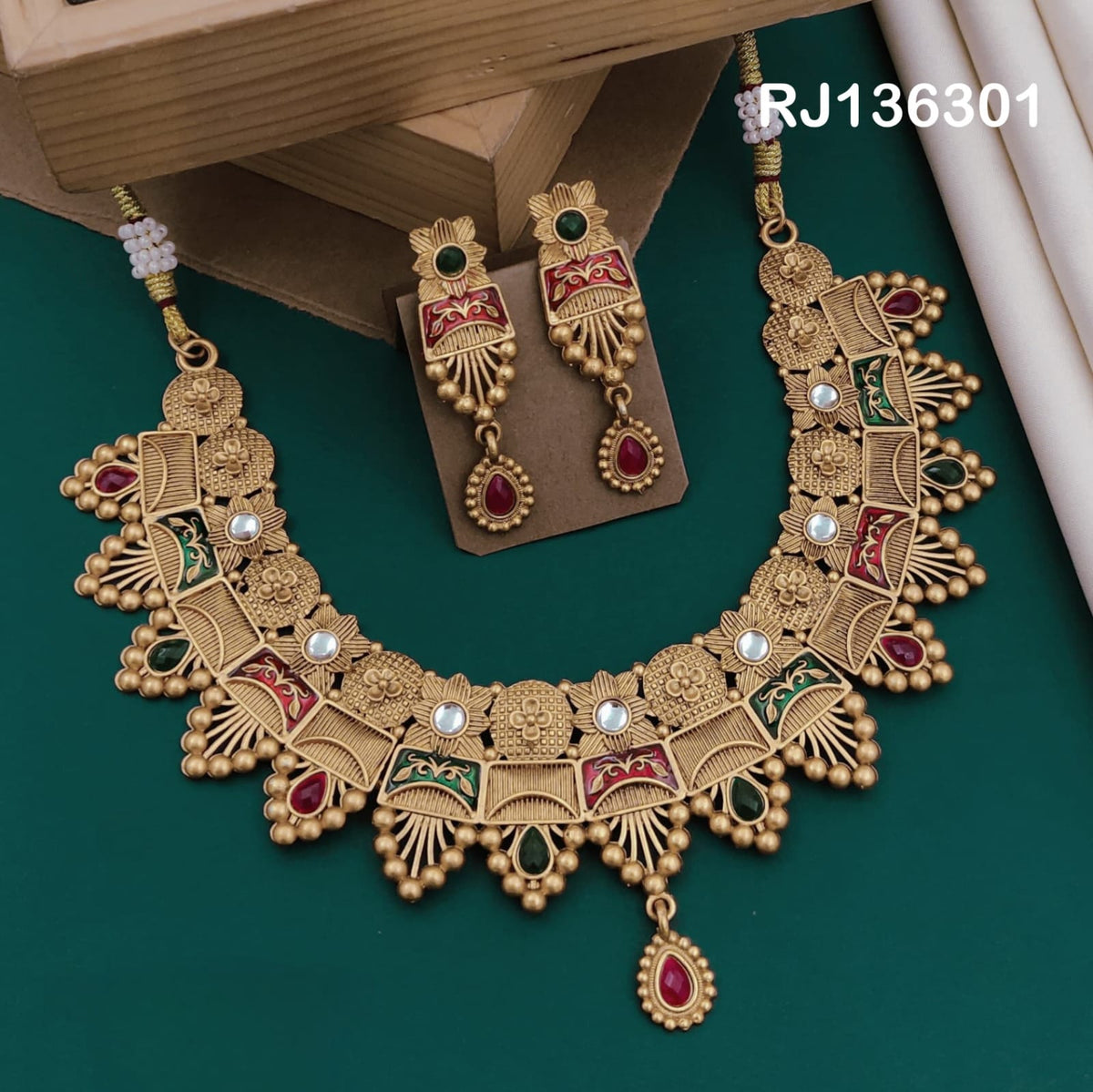Antique gold-tone necklace with fan-shaped motifs with red and green details, round beads and a red central drop, shown with coordinating drop earrings.