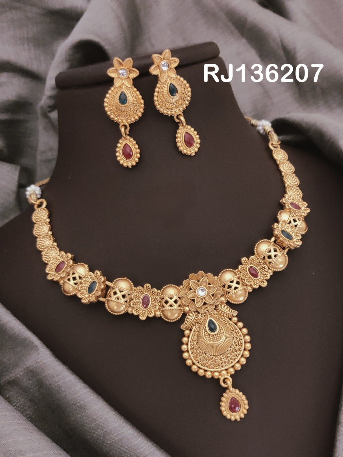 Antique gold-tone necklace with flower-shaped links, openwork details and a textured teardrop pendant, shown with coordinating drop earrings.