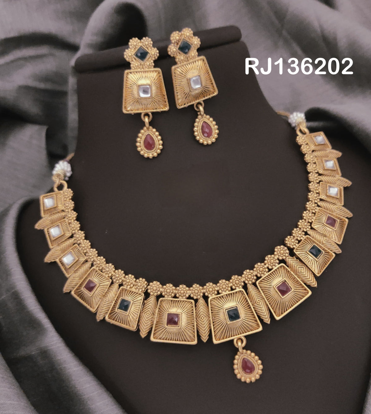 Antique gold-tone necklace with square panels with radiating lines, colored centers and a red drop, shown with coordinating drop earrings.