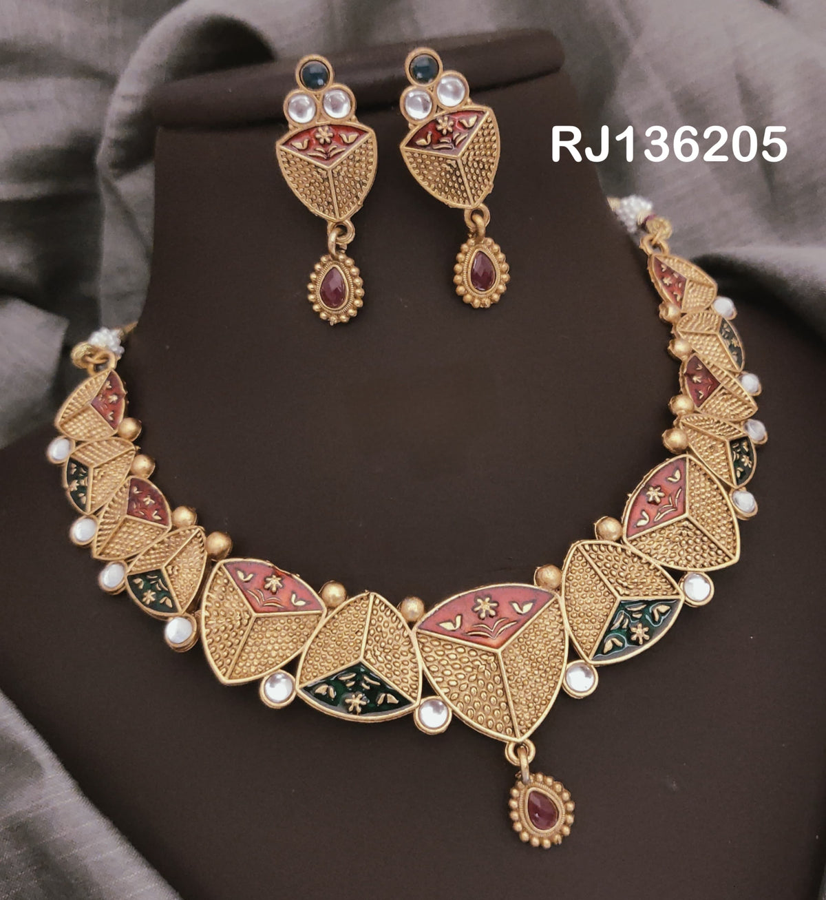 Antique gold-tone necklace with segmented leaf-shaped panels with red and green details and a red teardrop accent, shown with coordinating drop earrings.