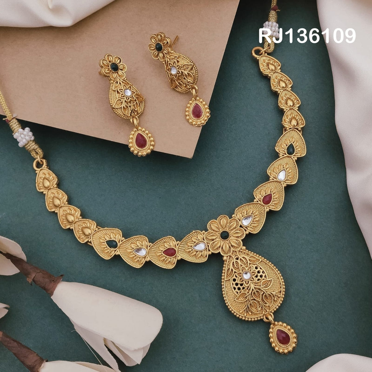 Antique gold-tone necklace with leaf-shaped links with colored accents, a floral center and an openwork teardrop pendant, shown with coordinating drop earrings.
