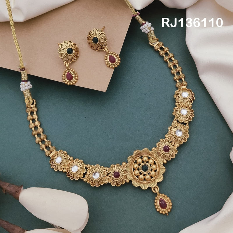 Antique gold-tone necklace with flower-shaped links, a round beaded center and a red drop, shown with coordinating drop earrings.