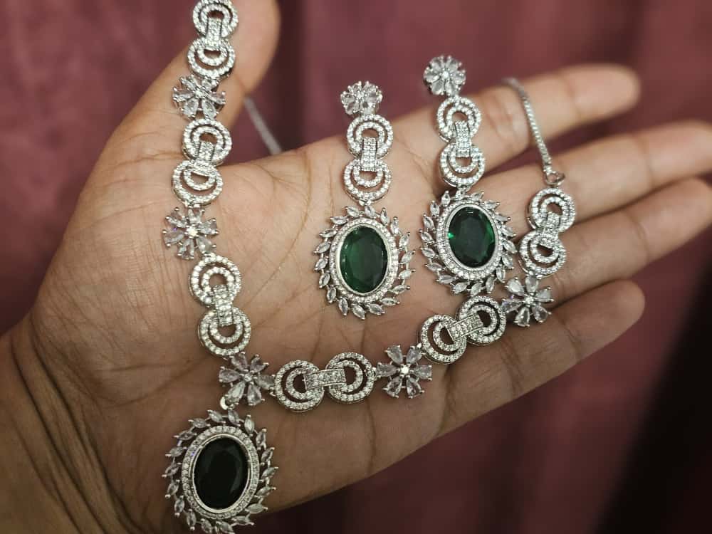 Emerald Green necklace with interlocking loop motifs, clear flower accents and a large oval center drop, shown with coordinating jewelry.