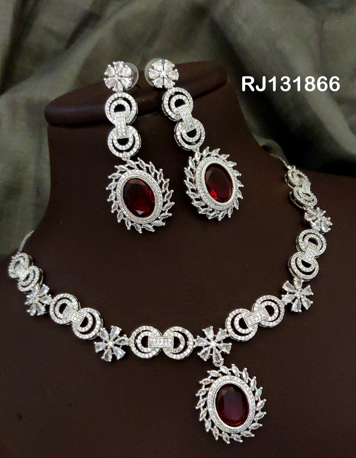 Ruby Red necklace with interlocking loop motifs, clear flower accents and a large oval center drop, shown with coordinating jewelry.