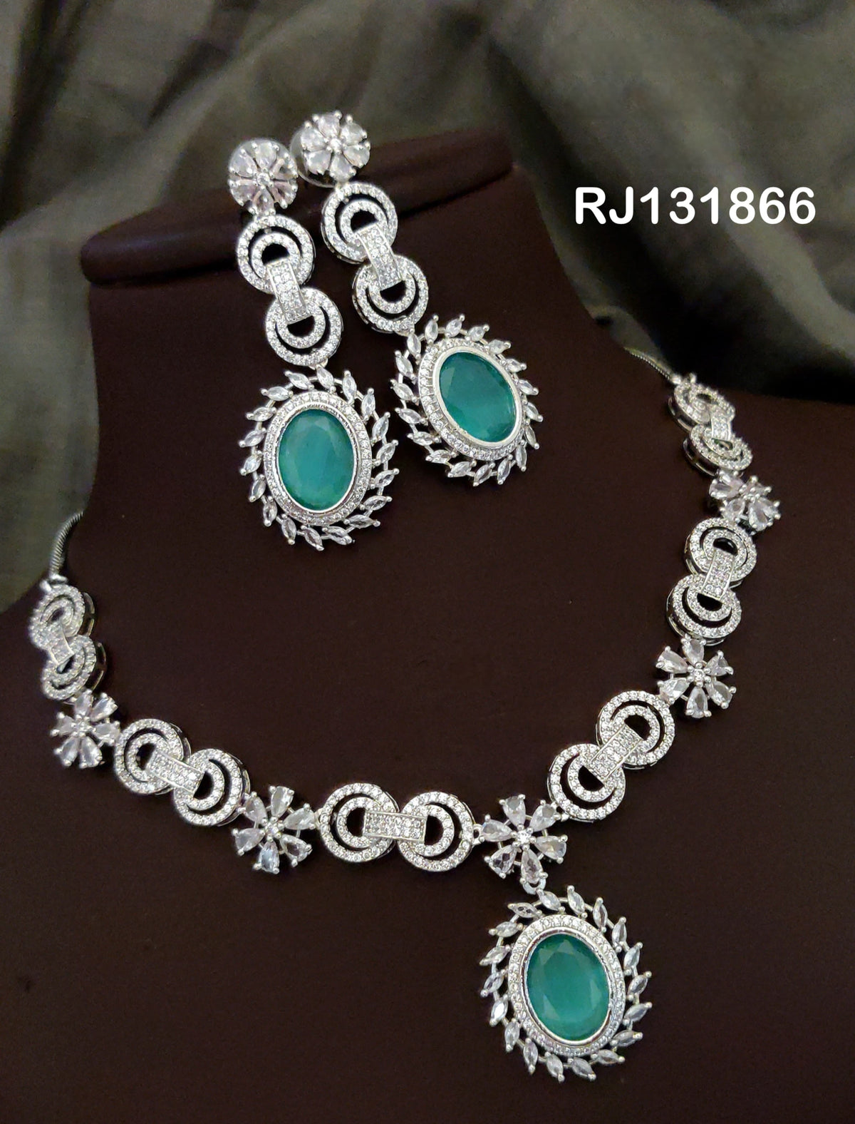 Turquoise necklace with interlocking loop motifs, clear flower accents and a large oval center drop, shown with coordinating jewelry.